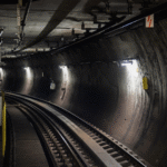Túnel ferroviário com cabos sensores instalados ao longo das paredes e do teto, utilizados para detecção linear de temperatura e prevenção de incêndios em ambientes subterrâneos.